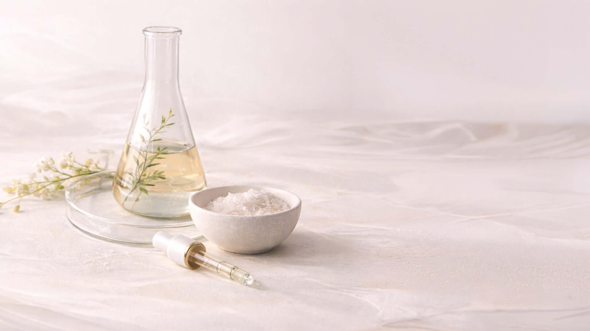 Skincare formulation ingredients with glass flask oil dropper and powder extract on soft background